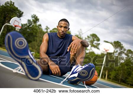 Young man sitting in a basketball court View Large Photo Image Stock Image - Young man sitting in a basketball court. Fotosearch