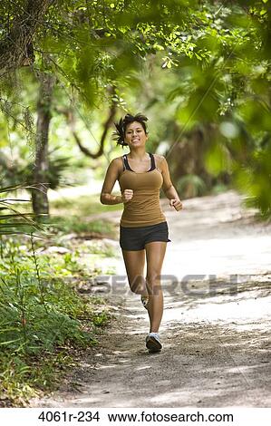 Young woman jogging in a park View Large Photo Image Picture - Young woman jogging in a park. Fotosearch