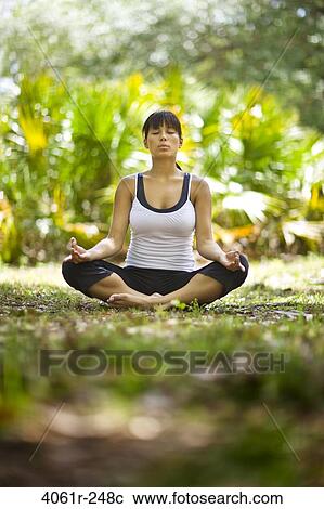Stock Image - Young woman practicing yoga in a park. Fotosearch