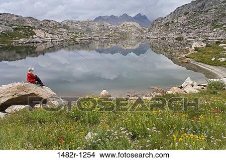 Hiker sitting on a rock at the lakeside, Bridger-Teton National Forest, Wyoming, USA View Large Photo Image Picture - Hiker sitting on a rock at the lakeside, Bridger-Teton National Forest, Wyoming, USA. Fotosearch