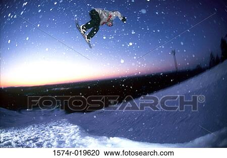 Stock Image - Low angle view of a man snowboarding. Fotosearch