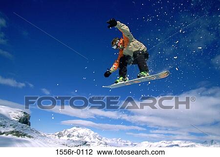 Stock Image - Man performing stunt on snowboard. Fotosearch