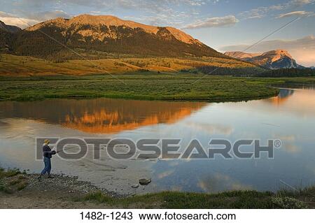 Stock Image - Person fly-fishing at the riverside, Green River, Bridger-Teton National Forest, Wyoming, USA. Fotosearch