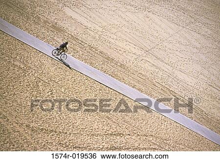 Stock Photograph - Person riding bicycle down road. Fotosearch