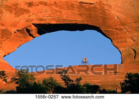 Stock Photo - Person riding bicycle in rock archway. Fotosearch