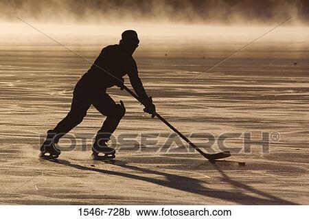 Stock Image - Silhouette of ice hockey player playing ice hockey. Fotosearch