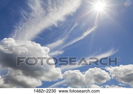 Stock Image - Summer sky and puffy clouds including the sun. Fotosearch