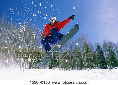 Stock Image - Teenager performing stunt on snowboard. Fotosearch