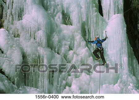 Stock Image - Young adult man ice climbing, Italy. Fotosearch
