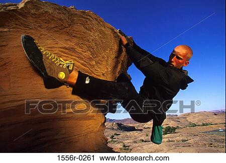 Stock Image - Young adult man mountain climbing, Utah, USA. Fotosearch