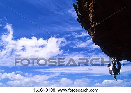 Stock Photo - Young adult man rock climbing. Fotosearch