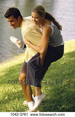 Stock Image - grass, people, water, couple, falling, lake, riding. Fotosearch