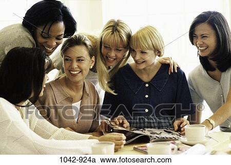 Stock Image - multiethnic, attentive, women, people, smiling, table, talking. Fotosearch