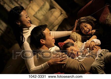 Stock Image - people, Asian, laughing, couch, family, embracing, embrace. Fotosearch