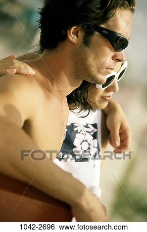 Stock Photograph - people, couple, beach, sunglasses, outdoors, hugging, watching. Fotosearch