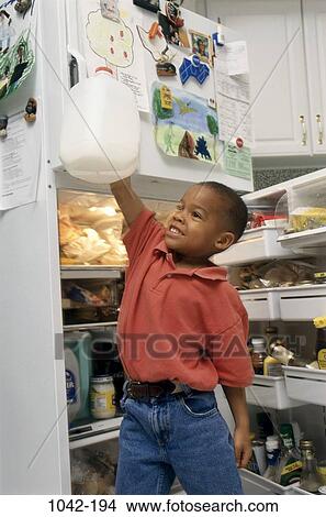 Picture - people, eating, door, milk, refrigerator, holding, boy. Fotosearch