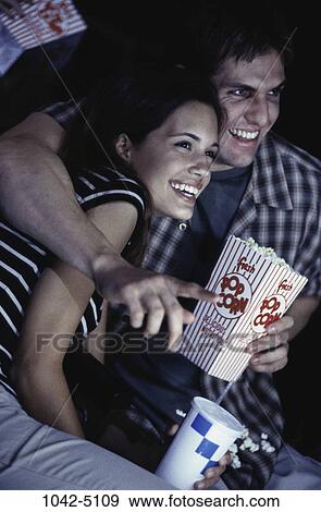 Stock Photo - people, smiling, couple, theater, popcorn, laughing, pointing. Fotosearch