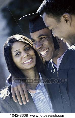 Stock Photo - people, smiling, outdoors, achievement, hugging, cap, smile. Fotosearch