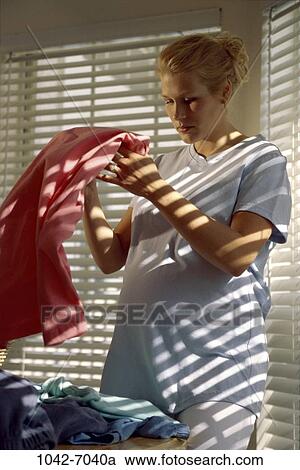 Stock Image - people, woman, shaking, blond, clothes, laundry, pregnancy. Fotosearch