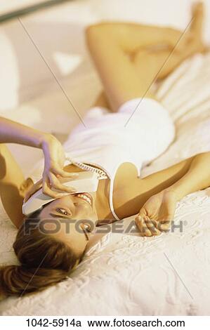 Stock Image - people, woman, telephone, talking, conversation, phone, bed. Fotosearch