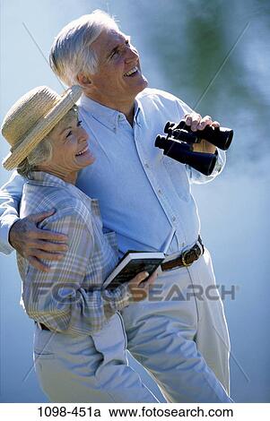Stock Image - people, hat, couple, binoculars, senior, laughing, book. Fotosearch
