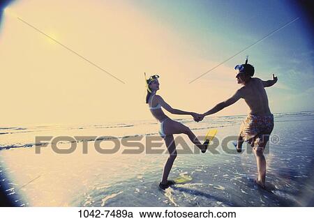 Stock Image - people, walking, couple, beach, outdoors, goggles, vacation. Fotosearch