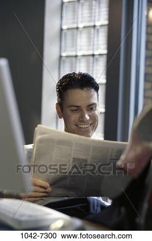 Stock Image - relaxed, paper, desk, smiling, newspaper, reading. Fotosearch