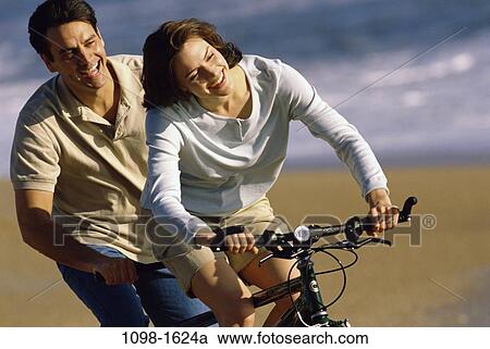 sand, people, water, smiling, couple, bicycle, beach View Large Photo Image Stock Image - sand, people, water, smiling, couple, bicycle, beach. Fotosearch
