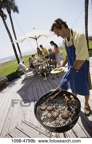 Stock Image - eating, smiling, table, umbrella, trees, outdoors, relaxing. Fotosearch