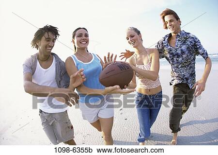 Stock Image - multiethnic, people, water, playing, beach, football. Fotosearch