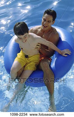 Picture - overhead, people, floating, water, pool, playing, inner tube. Fotosearch