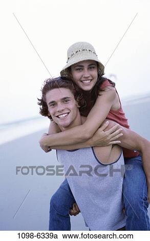 Stock Image - people, couple, beach, teens, piggyback, brunette, clothed. Fotosearch