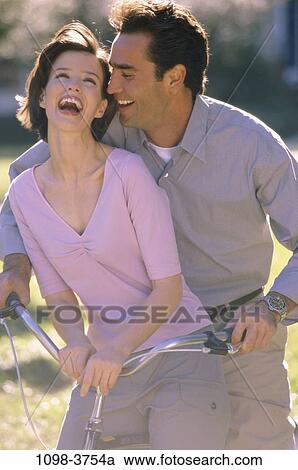 Stock Image - people, couple, steer, laughing, riding, outdoors, handlebars. Fotosearch
