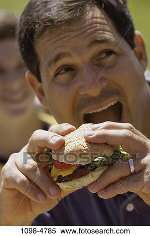people, eating, hamburger, holding, outdoors, Middle-aged View Large Photo Image Stock Photography - people, eating, hamburger, holding, outdoors, Middle-aged. Fotosearch