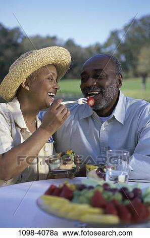 Stock Image - people, eating, table, hat, couple, sitting, senior. Fotosearch
