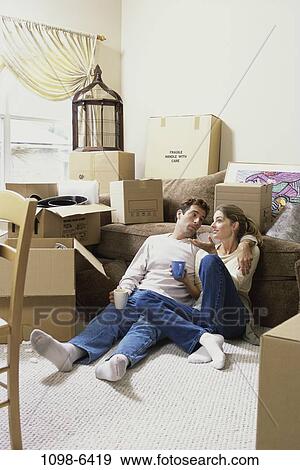 Stock Photo - people, home, moving, couple, coffee, drinking, couch. Fotosearch