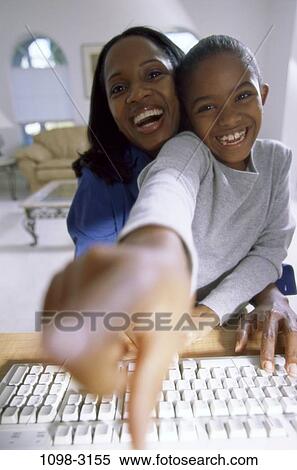 Stock Photography - people, home, technology, mother, computer, laughing, pointing. Fotosearch