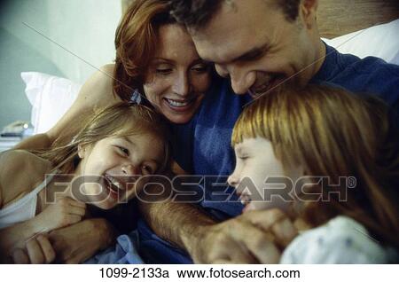 Stock Image - people, playing, bed, laughing, family, affection, play. Fotosearch