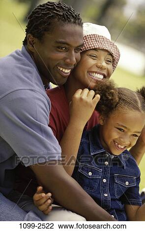 Stock Image - people, smiling, hat, sitting, laughing, outdoors, hugging. Fotosearch