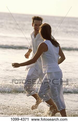 Stock Image - people, water, running, couple, racing, beach, splash. Fotosearch