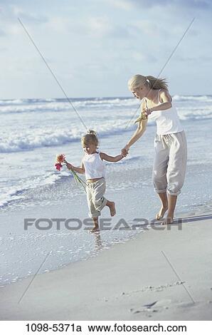 Stock Image - sand, people, hands, mother, holding, flowers, waves. Fotosearch