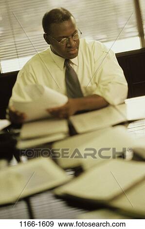 Stock Photo - desk, paperwork, eyeglasses, reading, business. Fotosearch