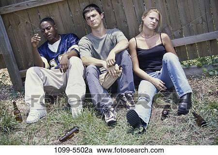 Stock Image - fence, multiethnic, cigarette, drinking, alcohol, smoking. Fotosearch
