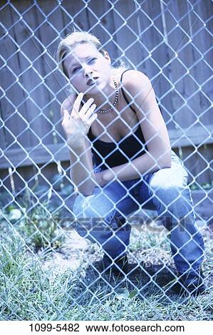 Stock Image - fence, people, woman, outdoors, lonely, sad, Caucasian. Fotosearch