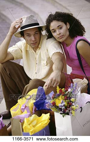 Stock Image - multiethnic, people, hat, couple, outdoors, shopping, shop. Fotosearch