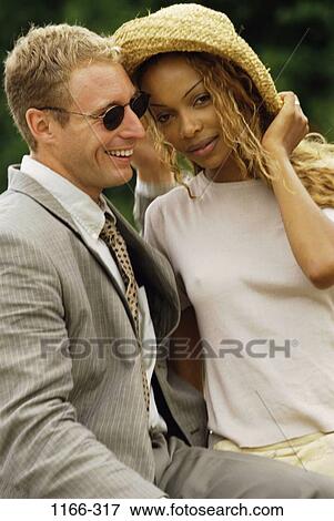 Stock Photo - multiethnic, people, hat, couple, sunglasses, outdoors, diversity. Fotosearch