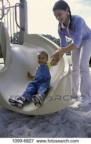 Stock Photo - multiethnic, people, playing, guiding, sliding, playground, outdoors. Fotosearch