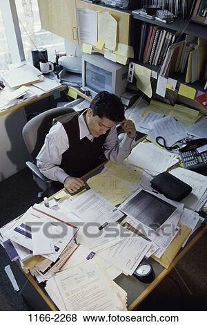 Stock Photo - overhead, desk, paperwork, Hispanic, reading, concentrating. Fotosearch