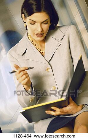 Picture - pen, woman, business, contemplation, planning, notes, brunette. Fotosearch