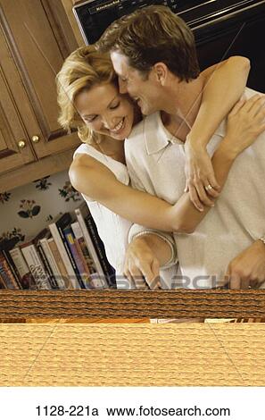 Stock Image - people, couple, books, cooking, laughing, Middle-aged, hugging. Fotosearch